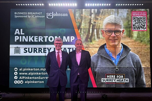 MP standing next to business breakfast screen